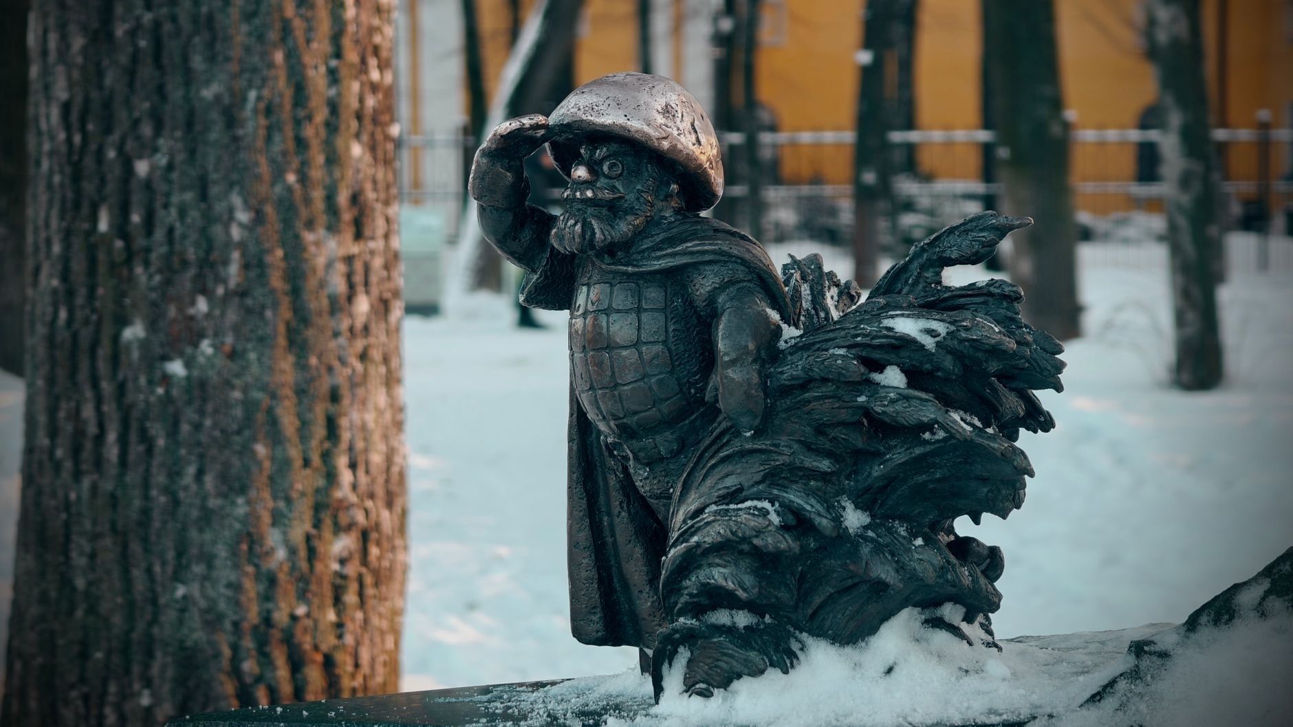 Bronzen beeldje met baard, helm en sneeuw in een winterse omgeving