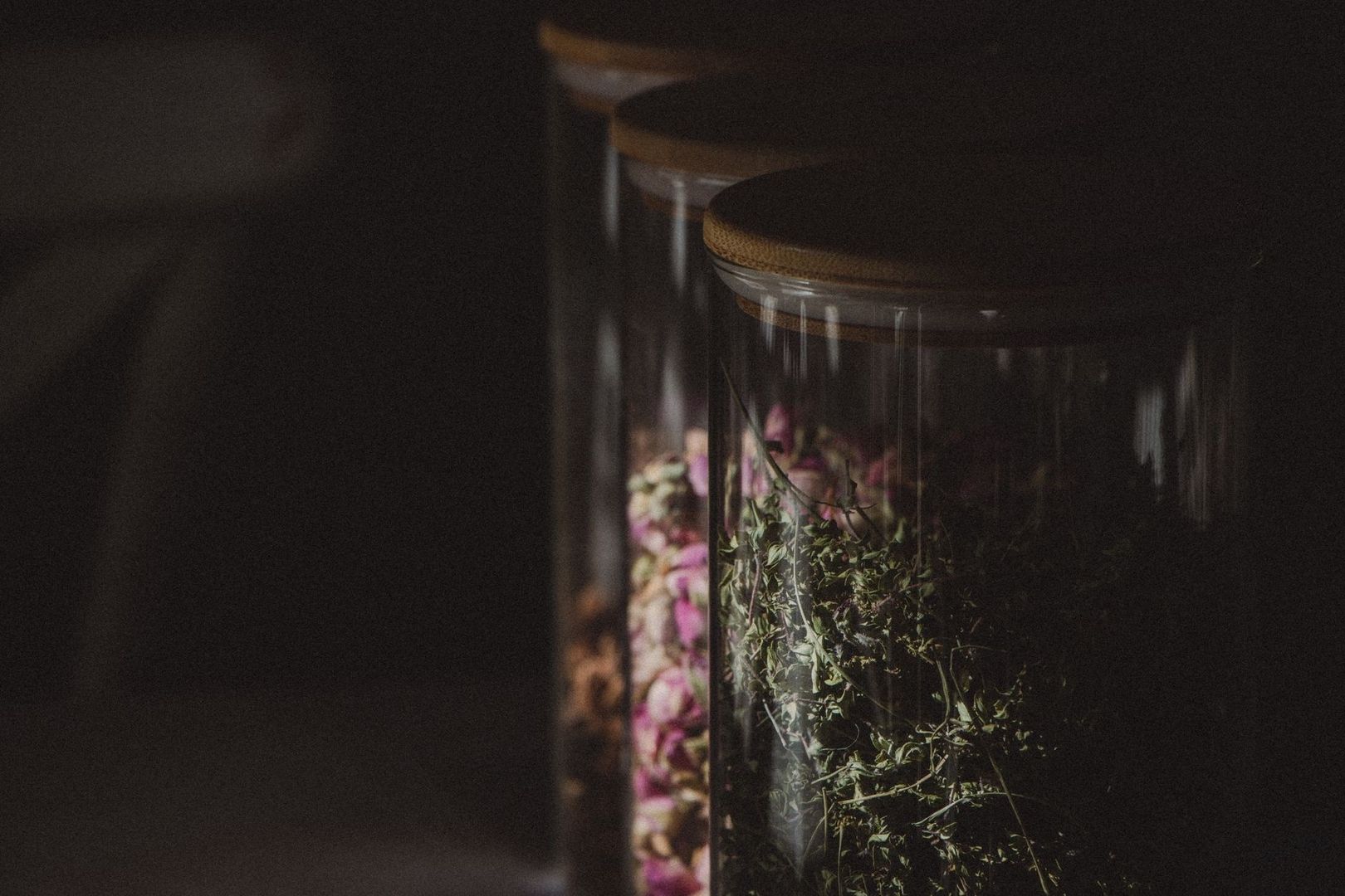 Donkere glazen apothekerspotten met gedroogde bloemen en kruiden